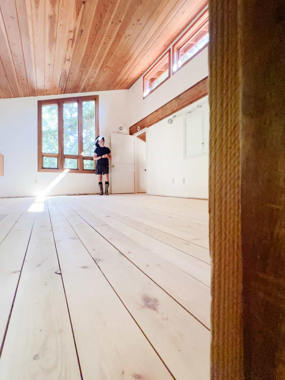 Anthony from 136 home standing in the cabin loft bedroom with the complete hardwood pine floors standing near the cathedral windows looking gorgeous.