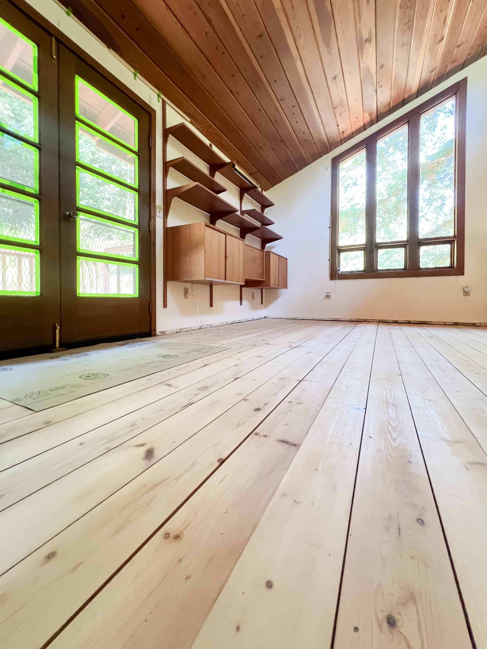 Hardwood pine floors freshly sanded with red wood ceilings and a wall mounted display unit empty.