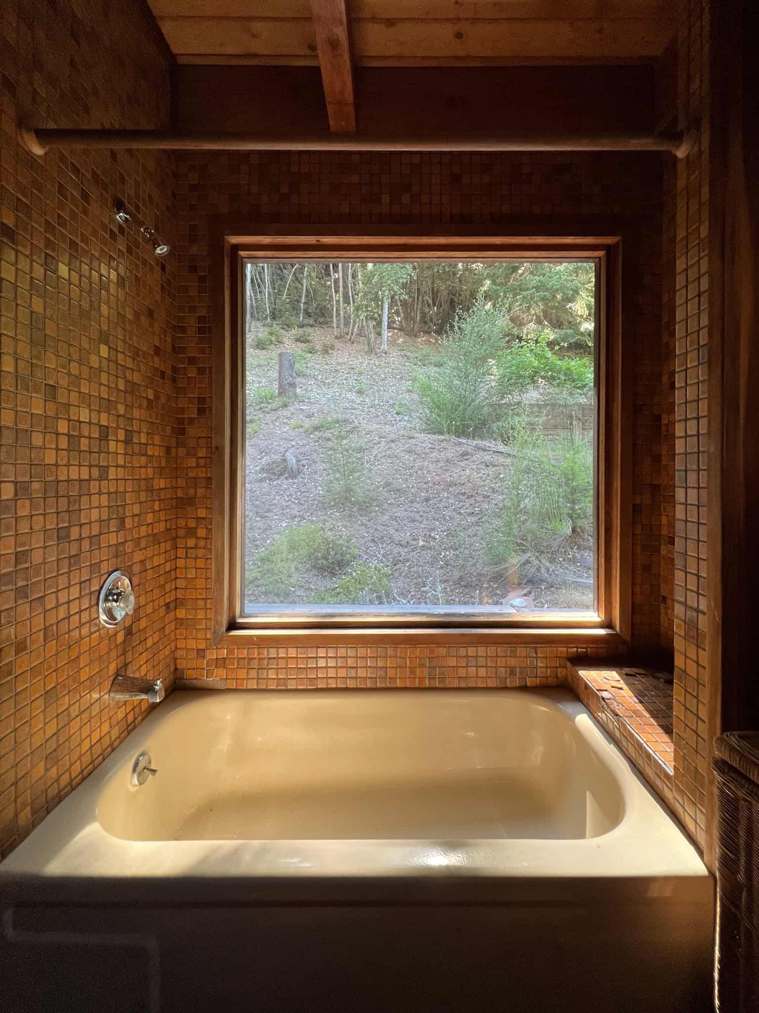 The original tub with failed tiles and a leaking tub that is tan and dingy. 