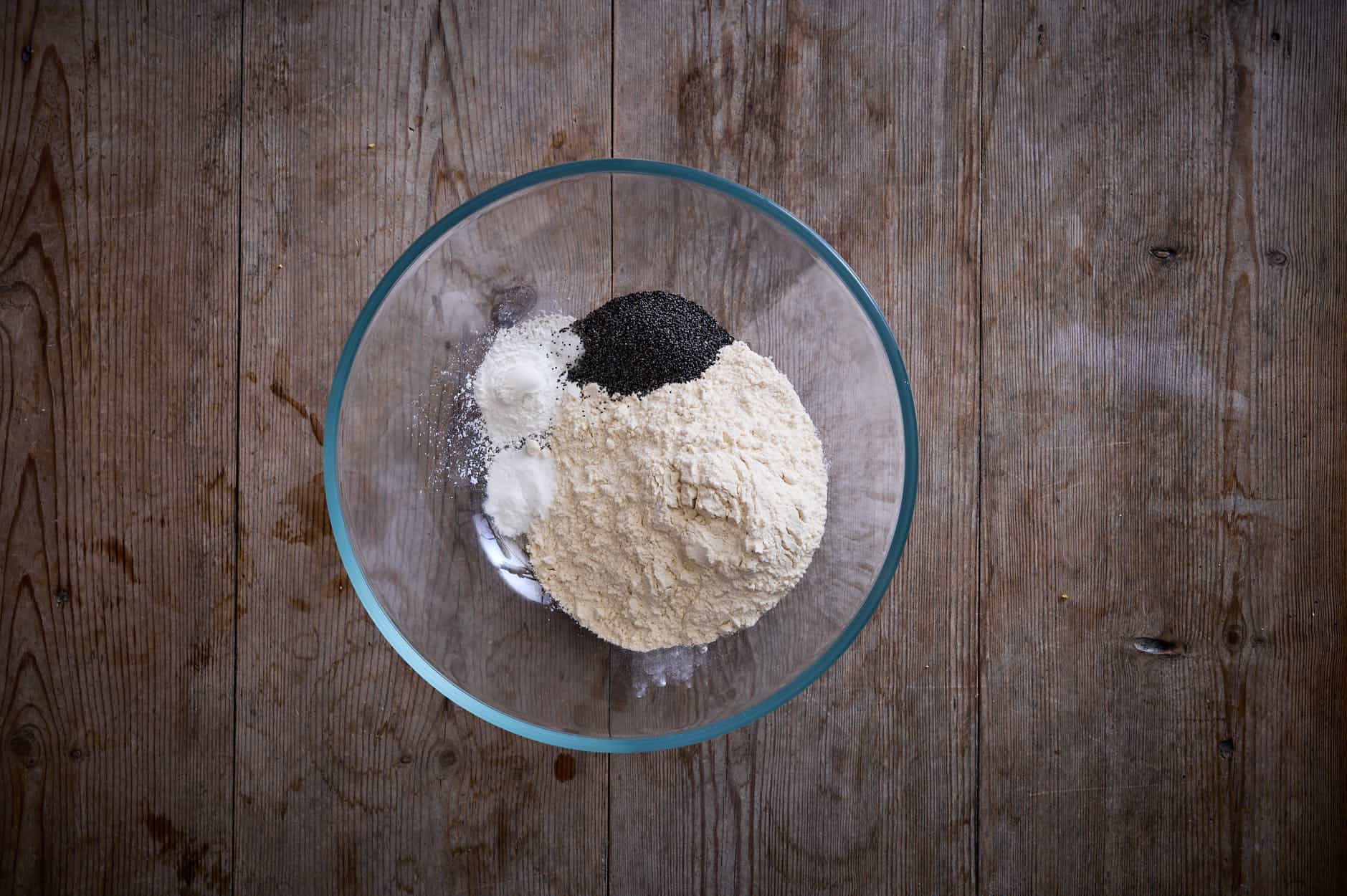 Poppy seed cake dry ingredients in a bowl to whisk that includes flour, baking soda and powder salt and poppy seeds. 