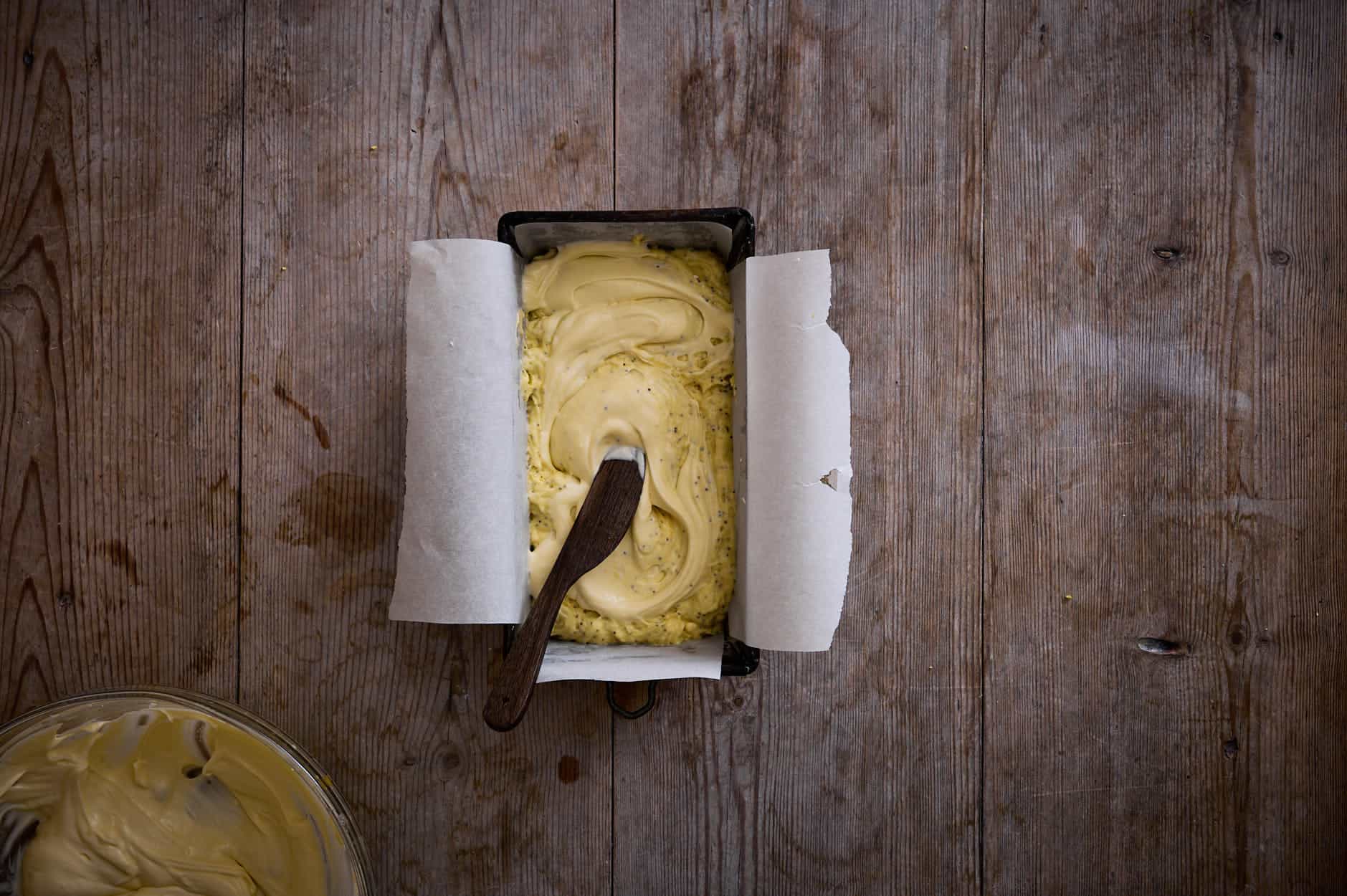 lemon and poppy seed cake batter poured and swirled into a loaf pan.