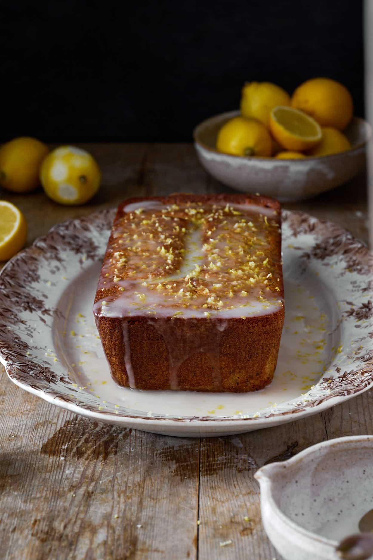 Close-up of tender crumb and poppy seeds in sliced lemon cake with fresh glaze and zest. 