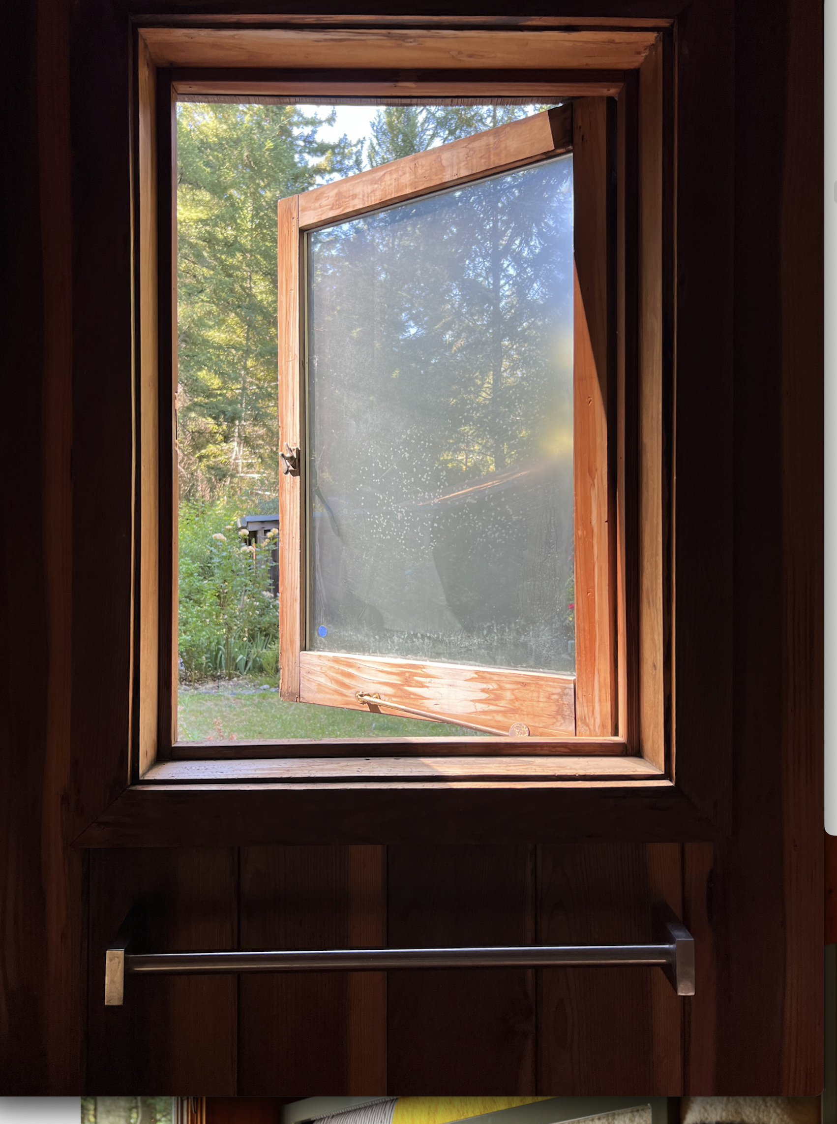 a casement window that is open made of redwood with windows that you can not see through.