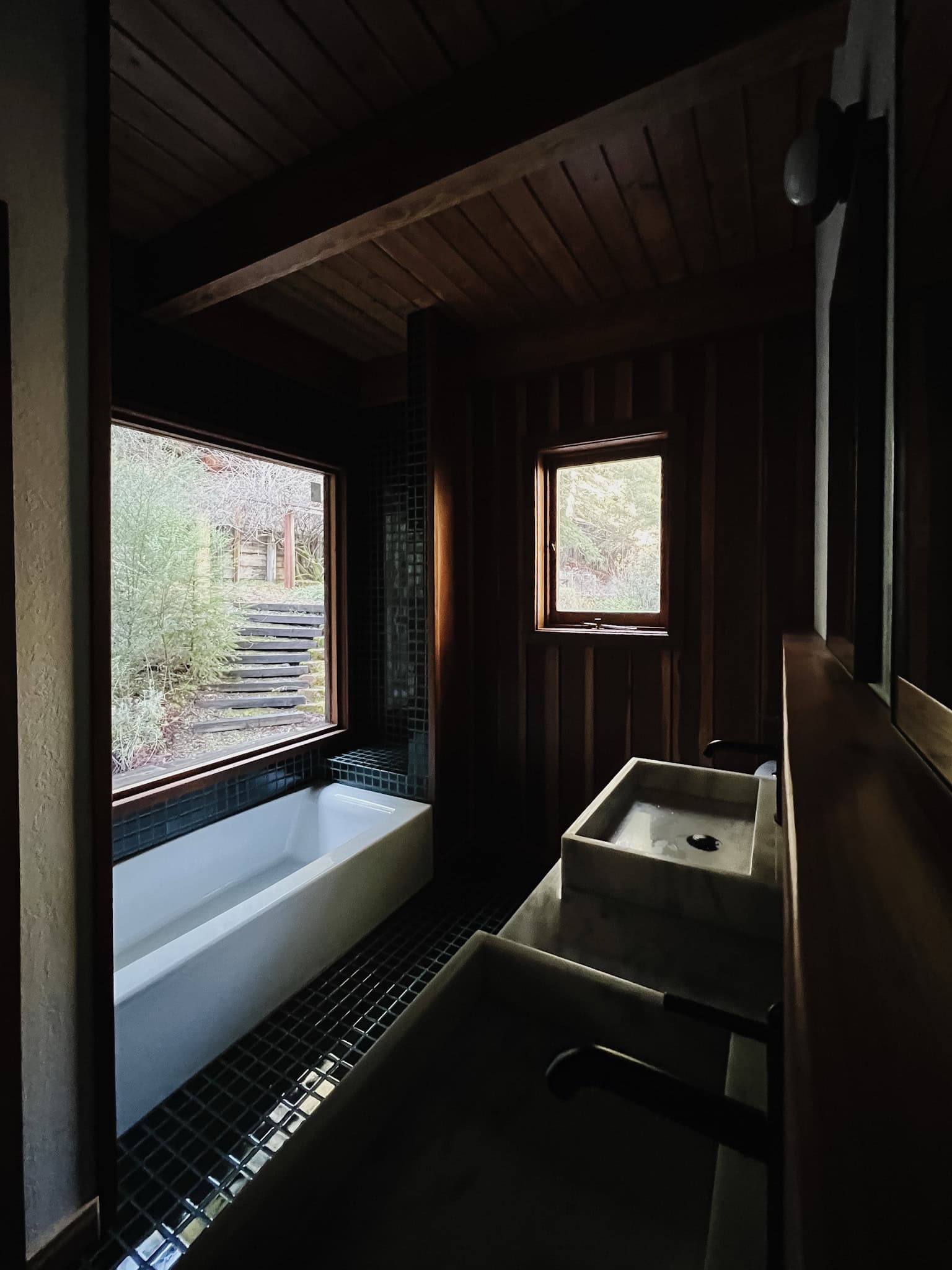 a wide view of the cabin bath with shiny green fireclay tile, and picture fraame window. 