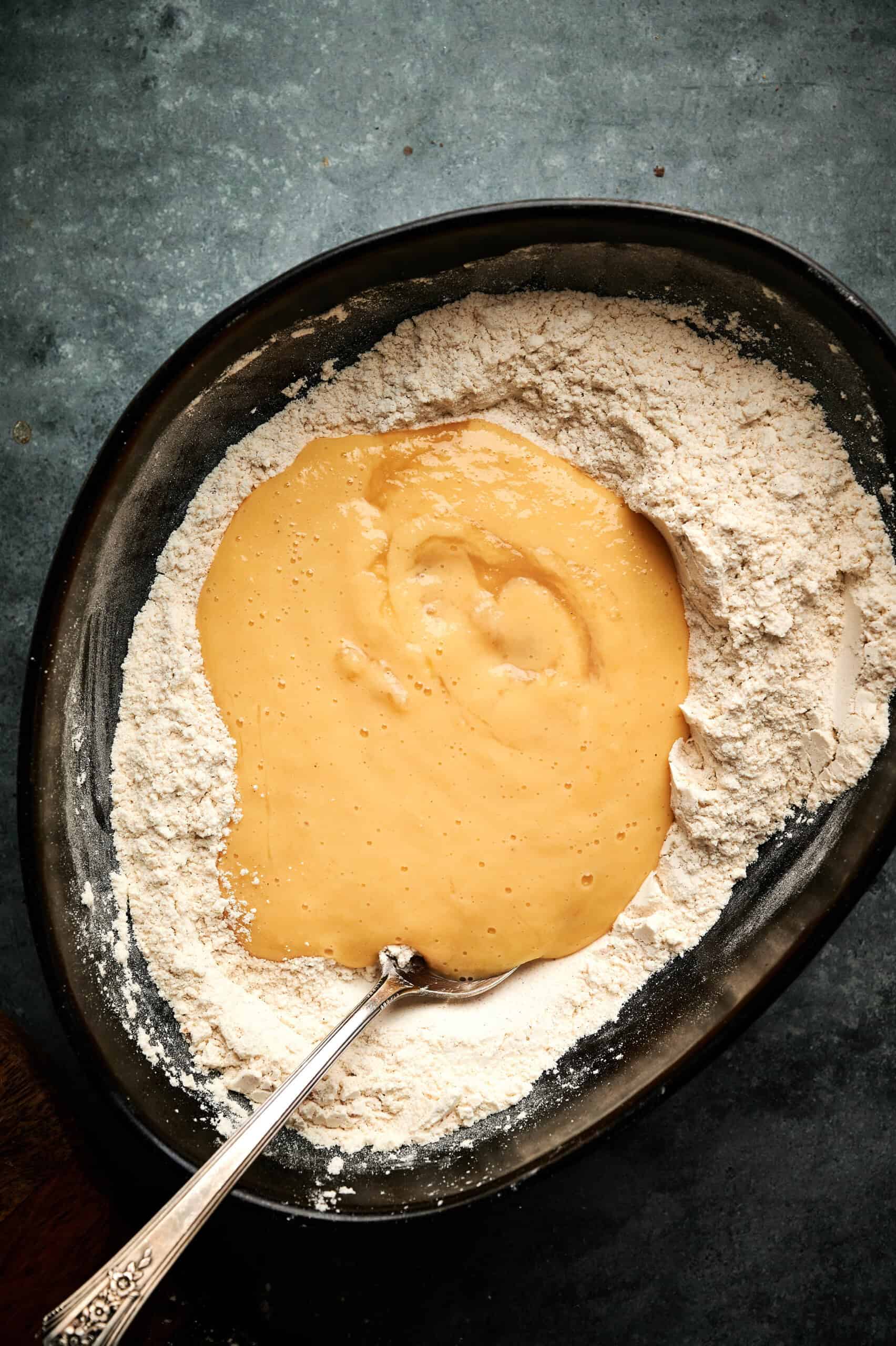 Applesauce mix being added to the dry ingredients to create a batter for fritters.