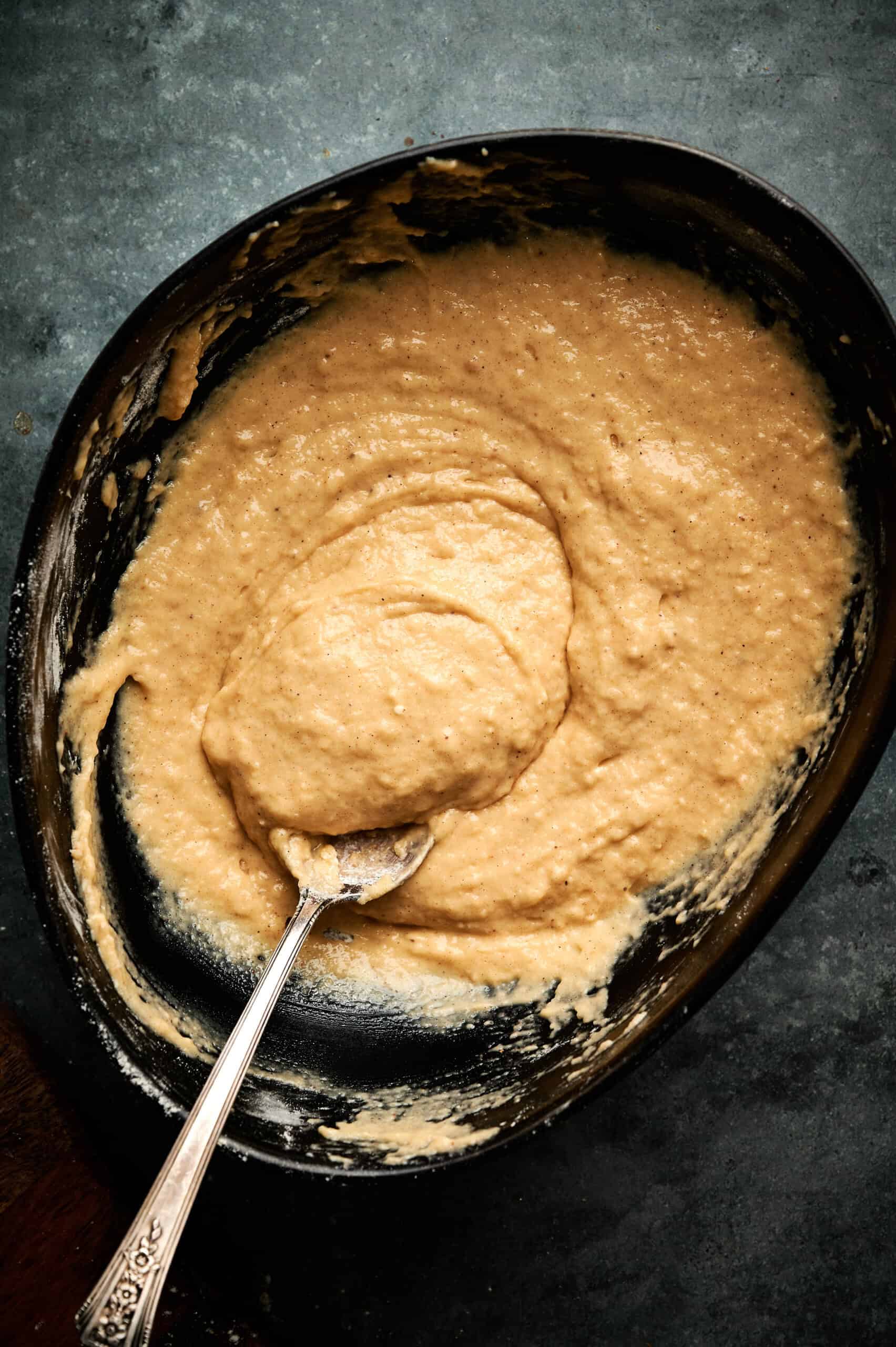 wet and dry ingredients combined to make applesauce fritters in a bowl. 