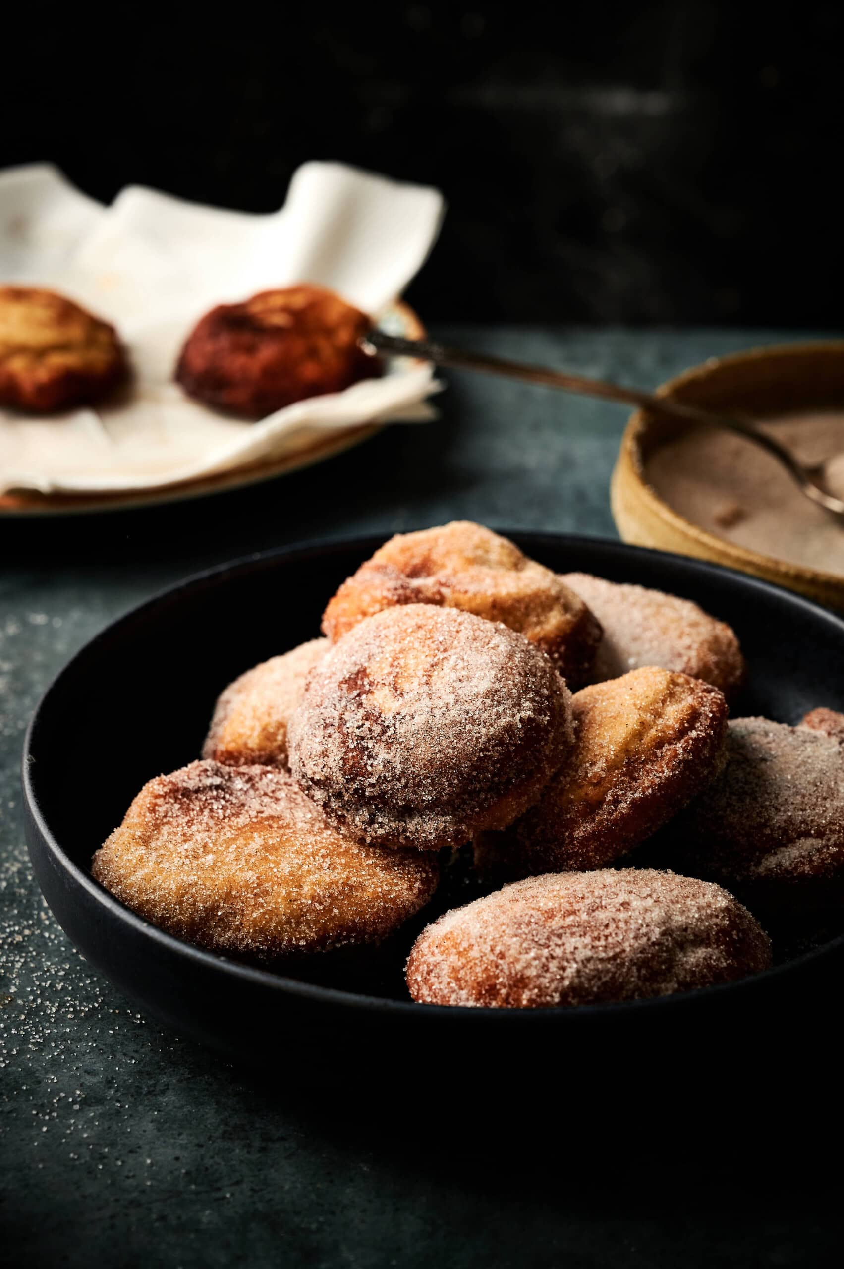 Applesauce fritters on a table with dusted sugar.