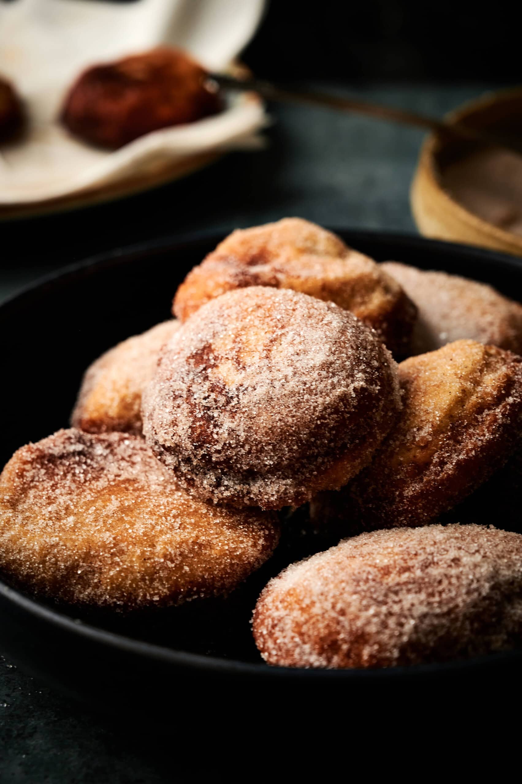 Fritters made from Gravenstein apples with applesauce as the batter, showing a plate of eight dusted in cinnamon and sugar. 