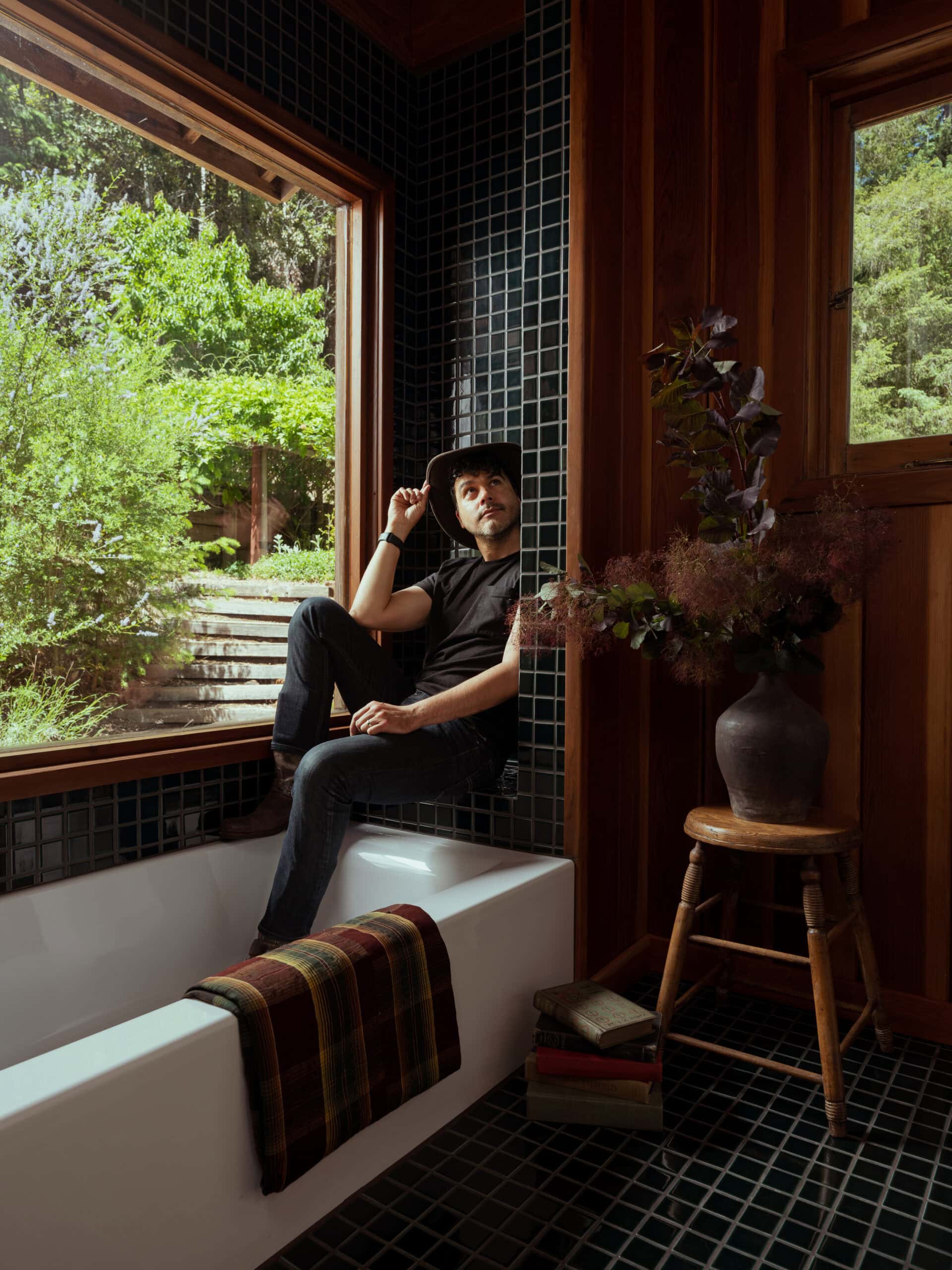 Anthony sitting in the new bath with a black shirt and cowboy hat - sitting in the shower bench.