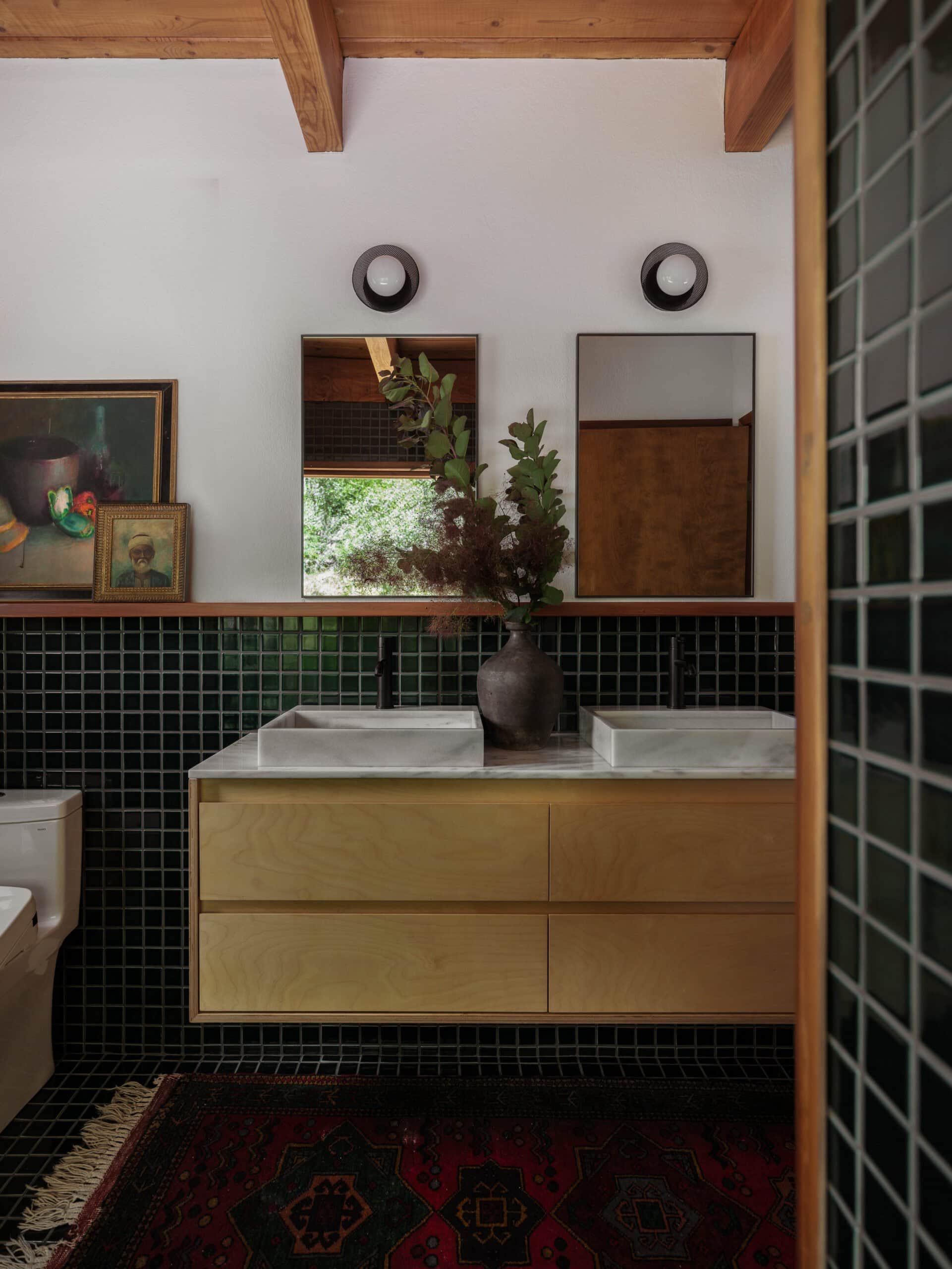 the new bath in the cabin with two pieces of vintage art featuring a vintage vase with stems and marble countertops.