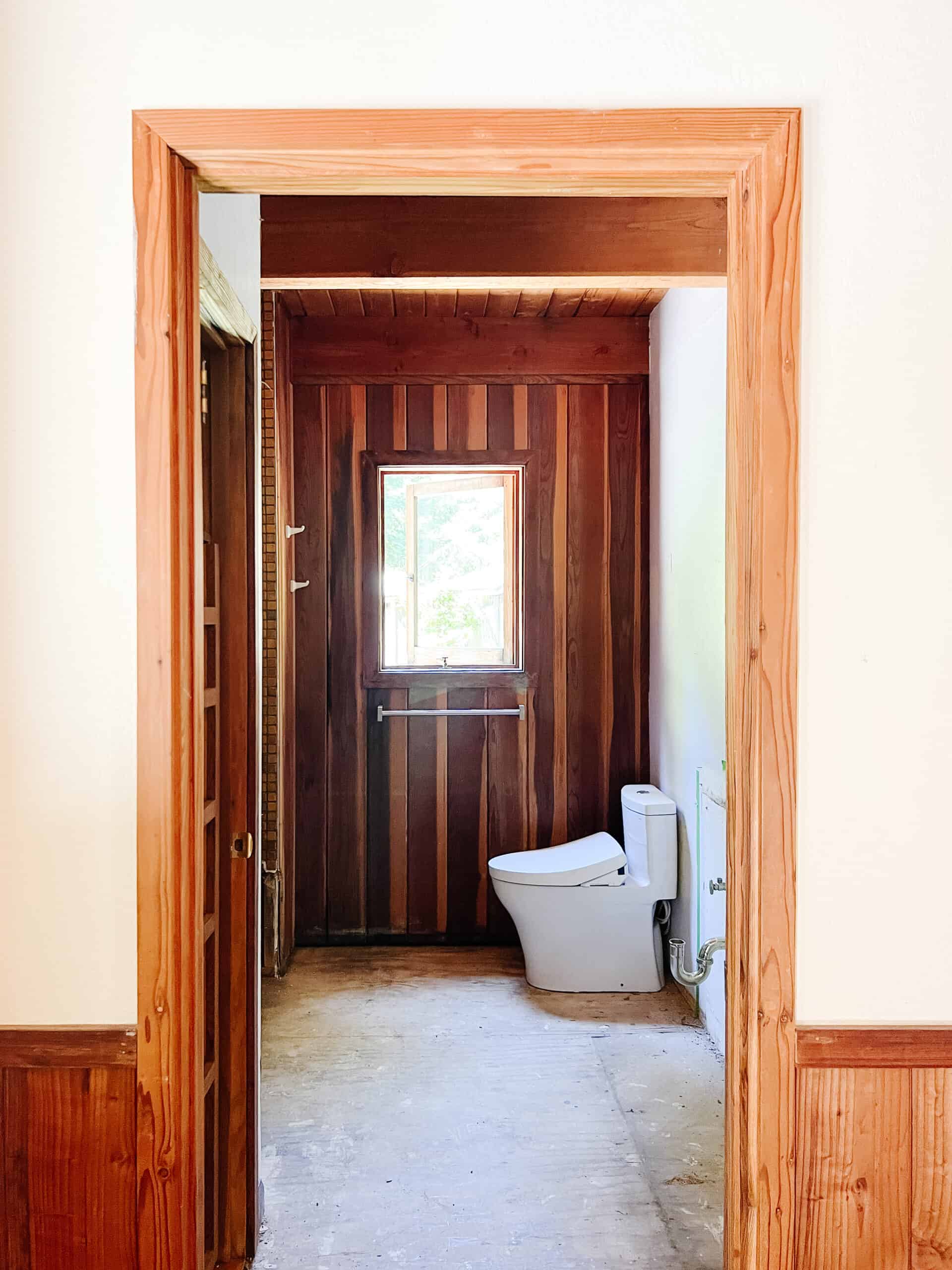 the before image of a door frame with a toiler and window with no floors. 