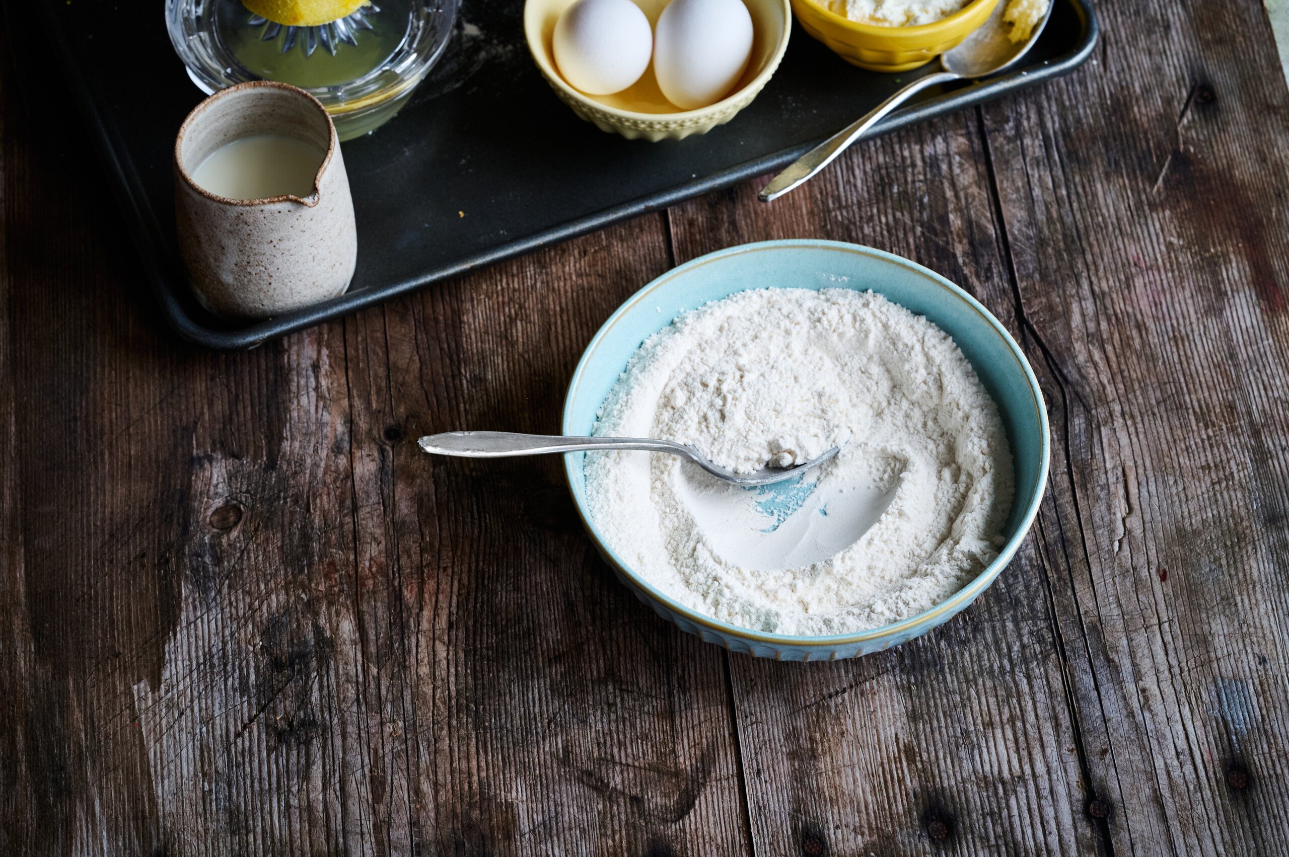 dry ingredients for Lemon and Ricotta Pancakes on a table with a spoon.