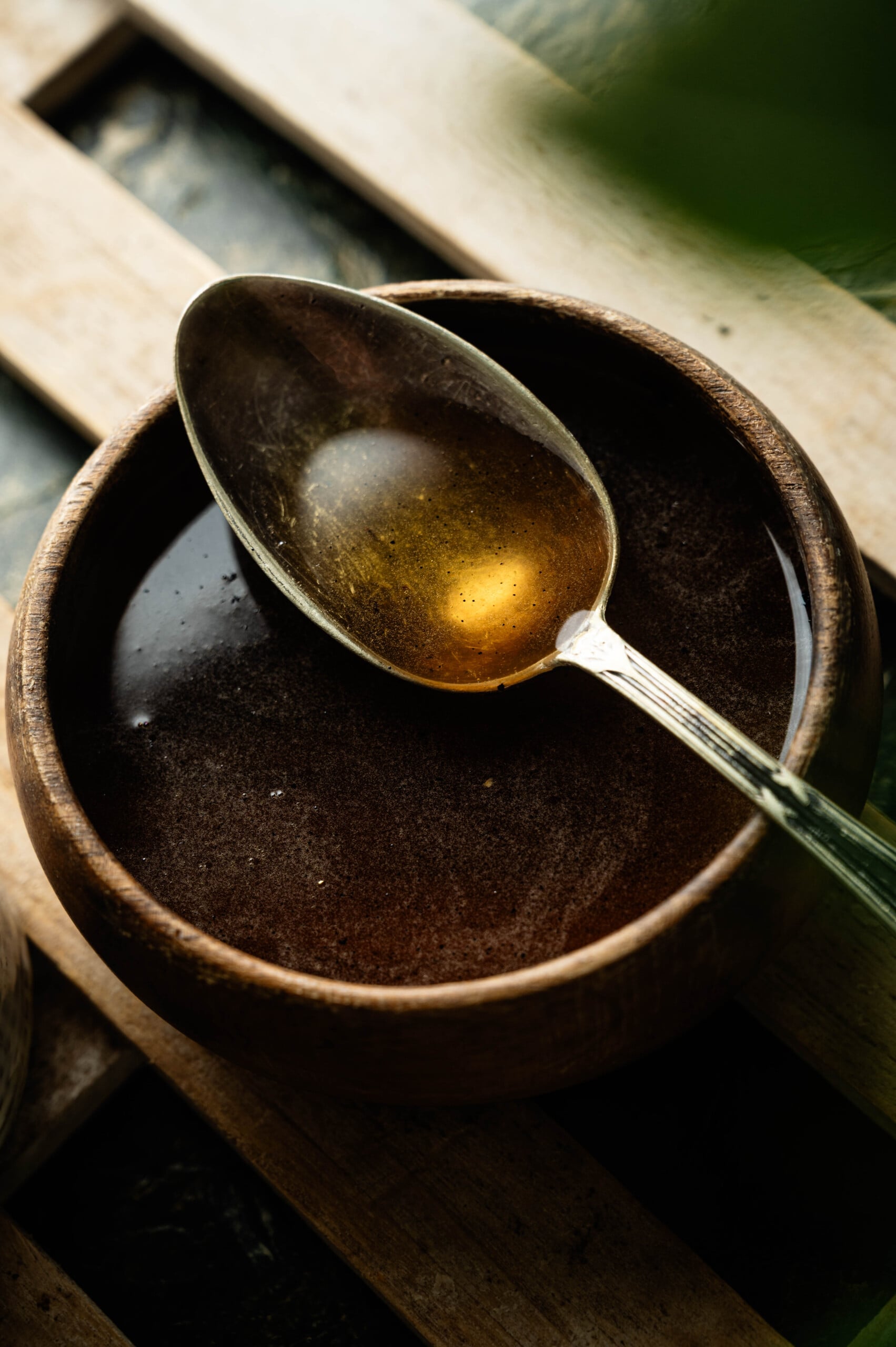 poached pear recipe syrup in a wooden bowl with a spoon.