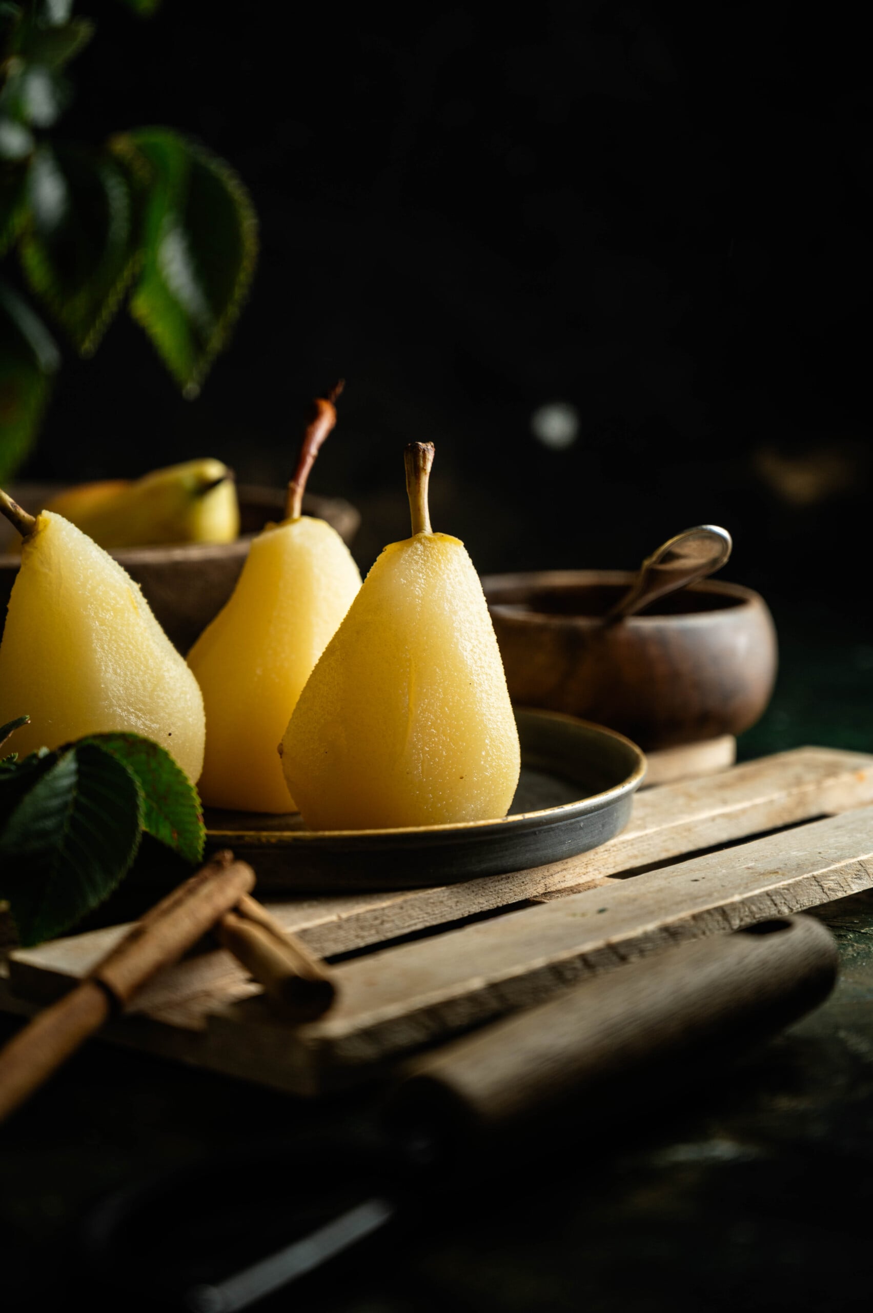 Testing a poached pear with a knife to check if the fruit is tender.