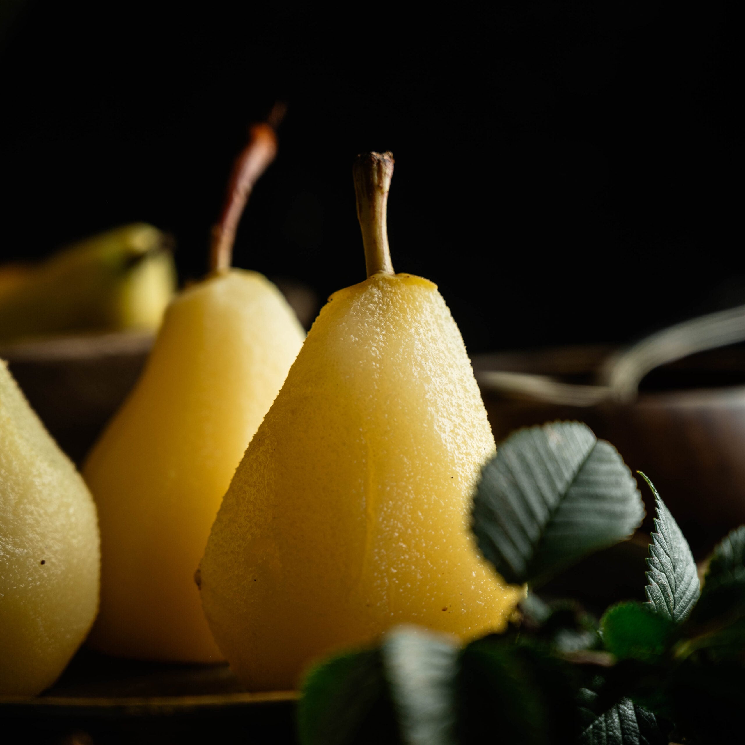 Peeled pears with stems attached already for poached and on disply.