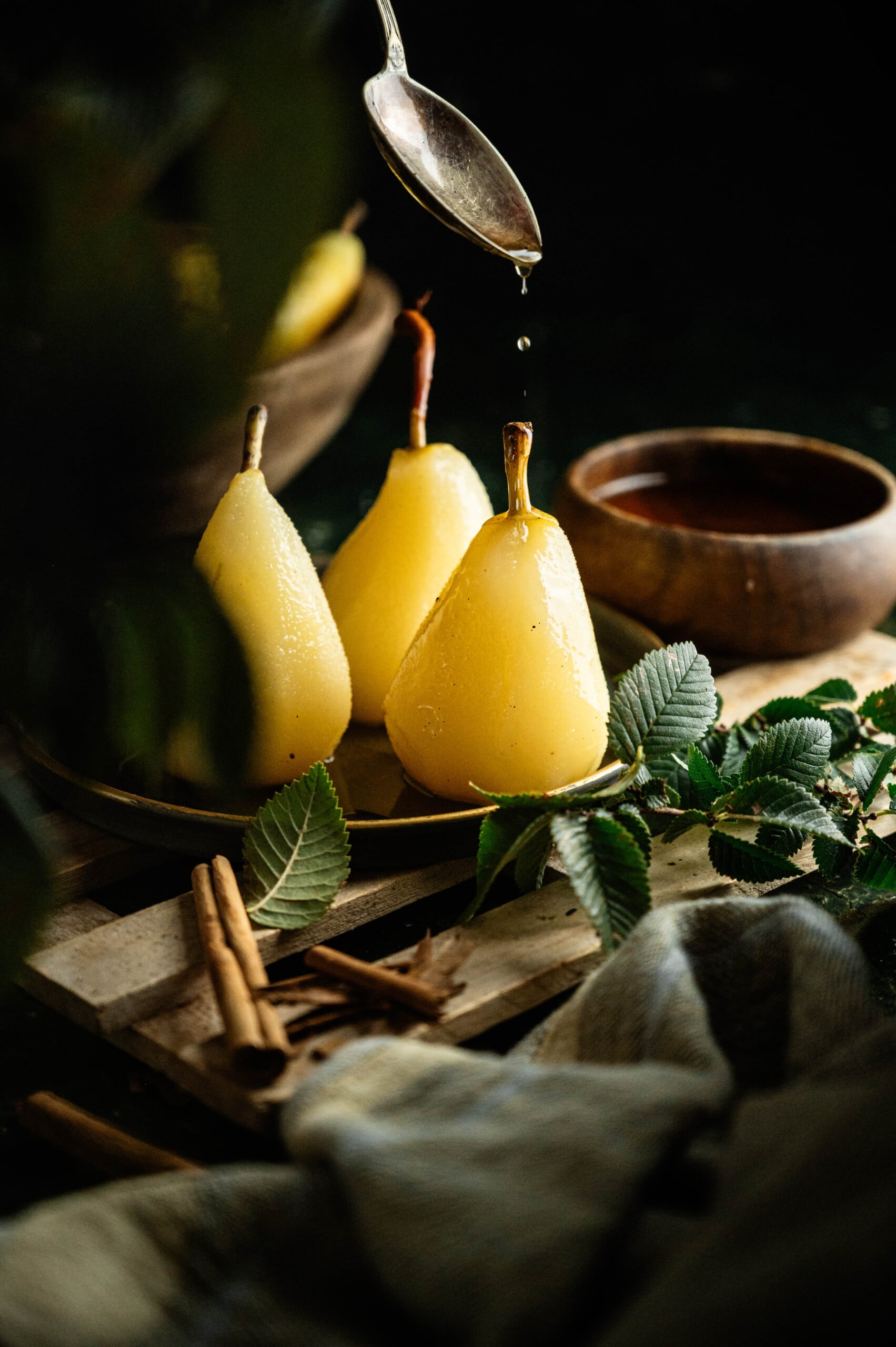 drizzling syrup on a plate of pears made from an easy poach pears recipe.